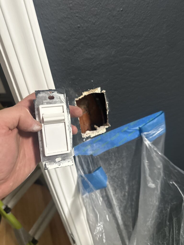Electrician removing a dimmer switch during a residential lighting repair in Burlingame, CA
