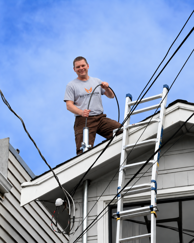 Licensed electrician from ELC Contractor standing on a ladder at a residential job site in San Bruno, CA
