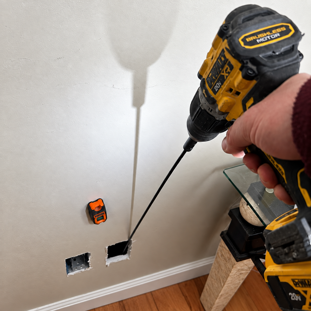 Technician investigating a concealed electrical route through a targeted wall opening